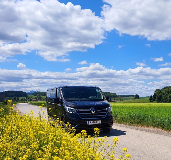 Taxi Kräftner 86100 neuer Renault Bus zwischen Rapsfeld und wogendem Weizenfeld in grüner Hügellandschaft